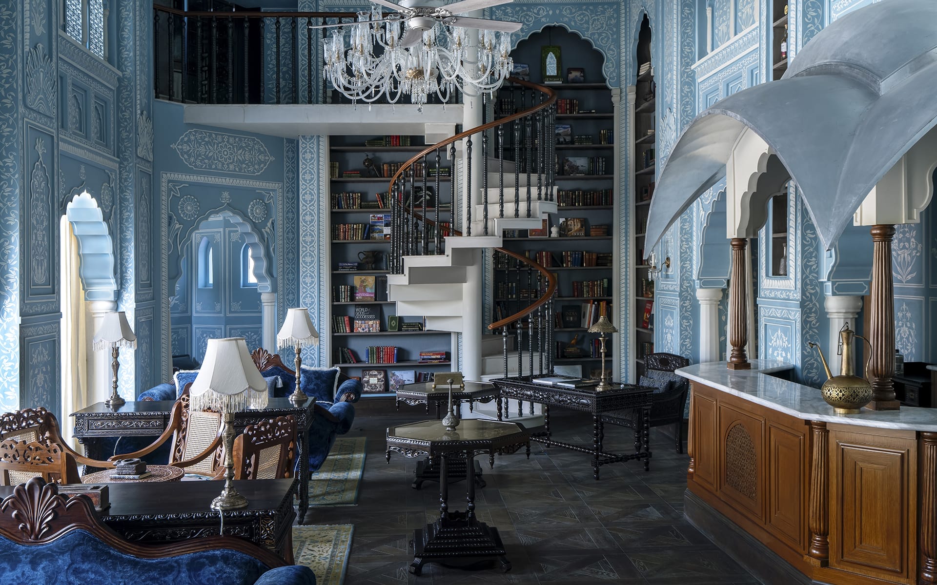 Elegant blue-themed library with spiral staircase, ornate furniture, chandeliers, and detailed wall designs.