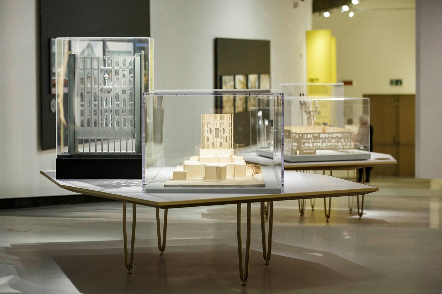 Exhibit of architectural models displayed in a well-lit museum gallery setting.