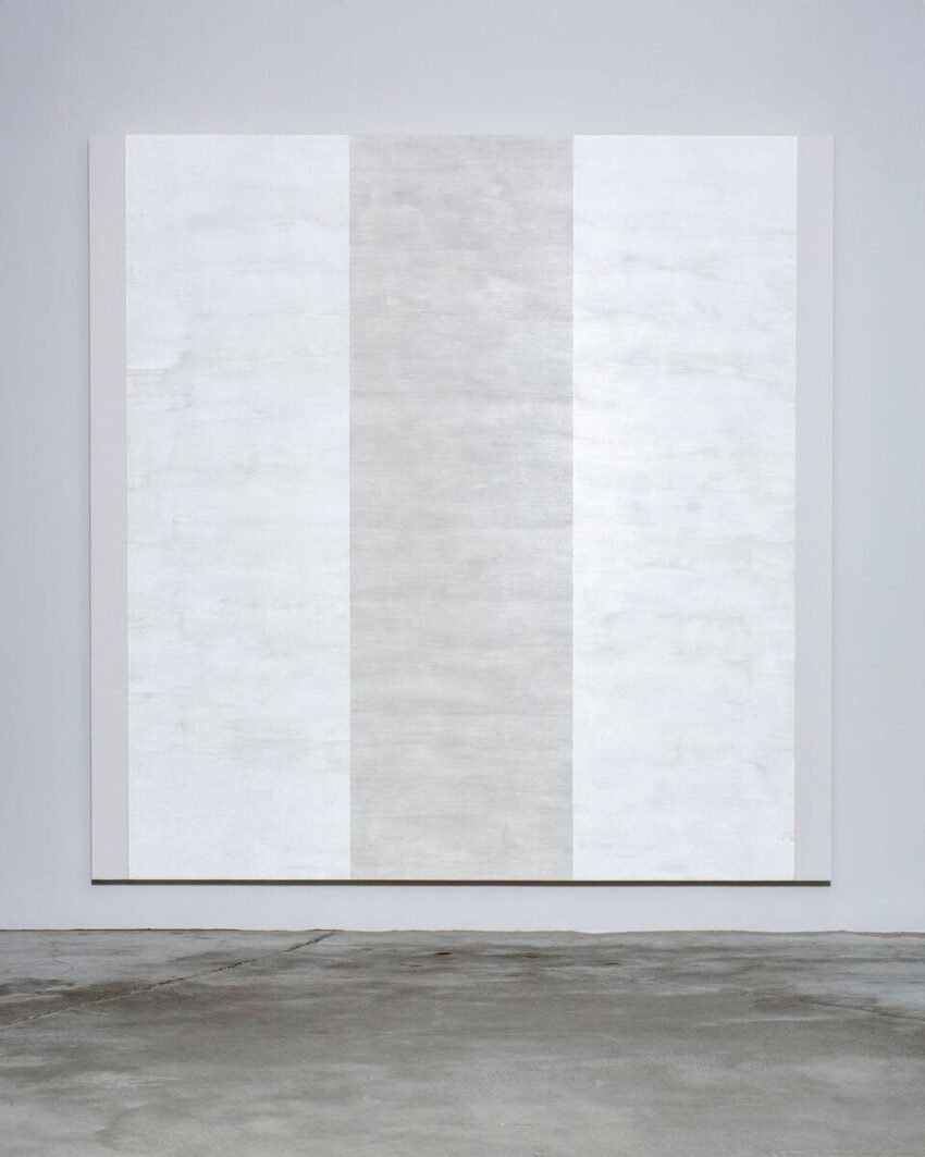 Abstract painting with three vertical white panels on a gray wall background.