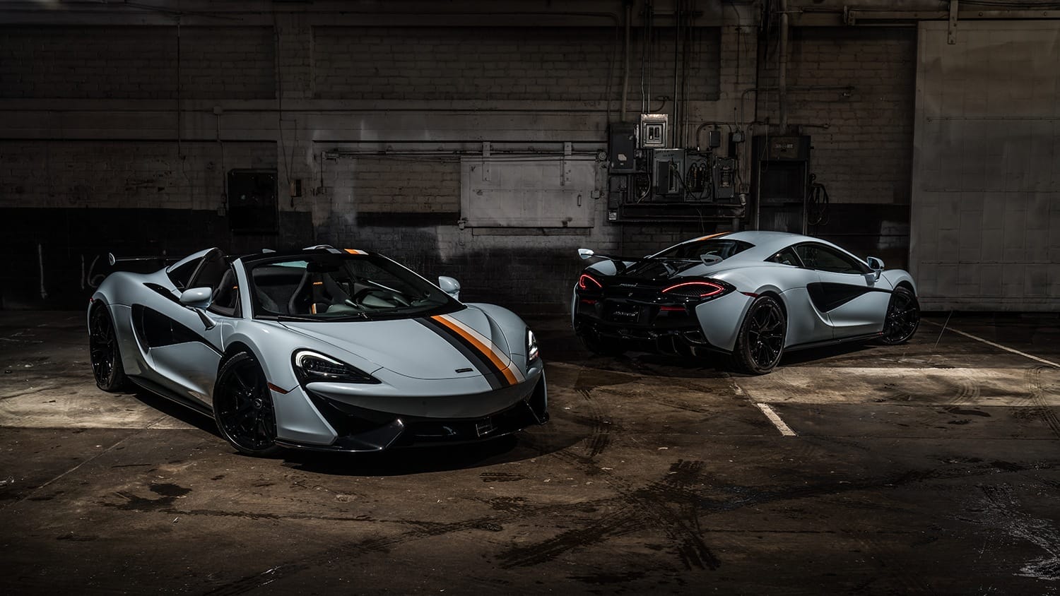 Two sleek sports cars parked in a dimly lit garage, showcasing aerodynamic design and luxury features.