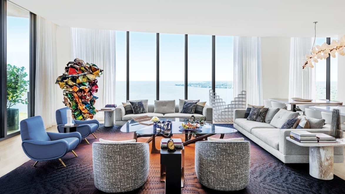 Modern living room with large windows, contemporary furniture, abstract artwork, and ocean view.