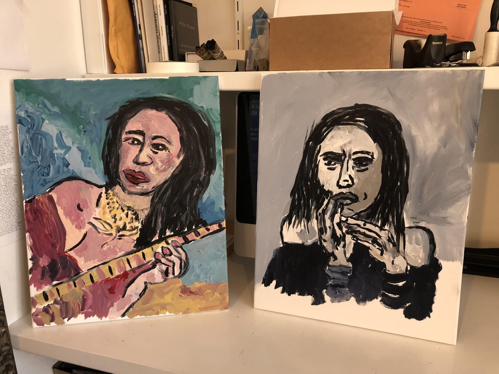 Two expressive abstract paintings of a woman, one holding a flute and the other in contemplative pose, on a shelf.