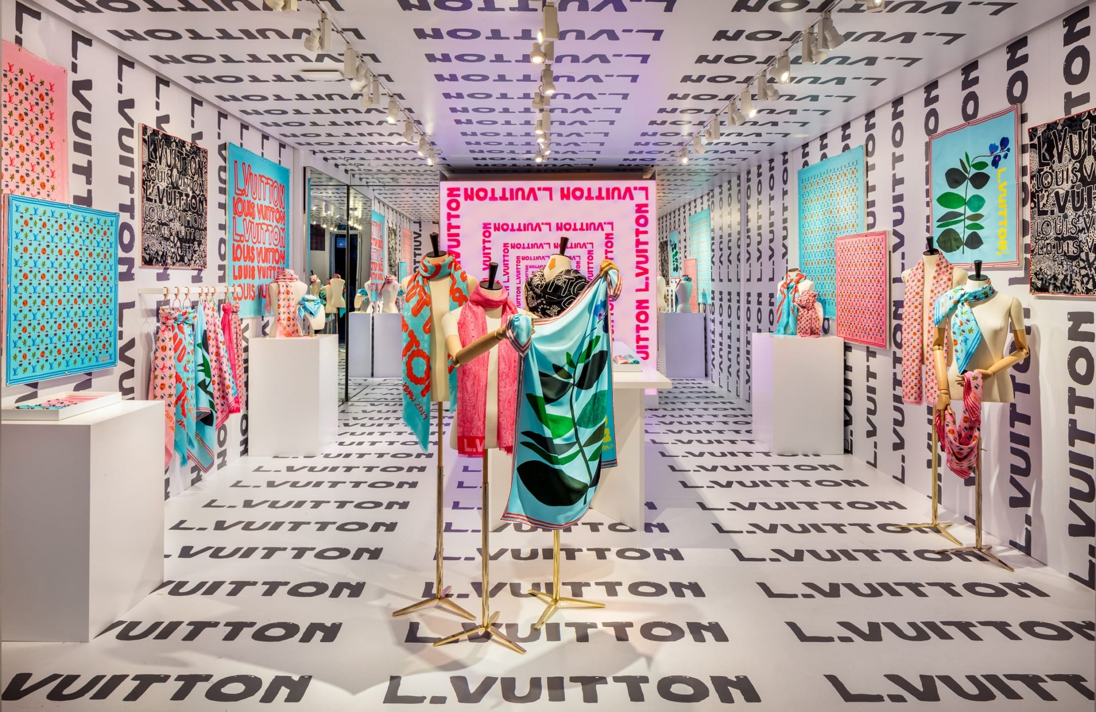 Colorful Louis Vuitton fashion store interior with mannequins, patterned walls, and vibrant clothing displays.