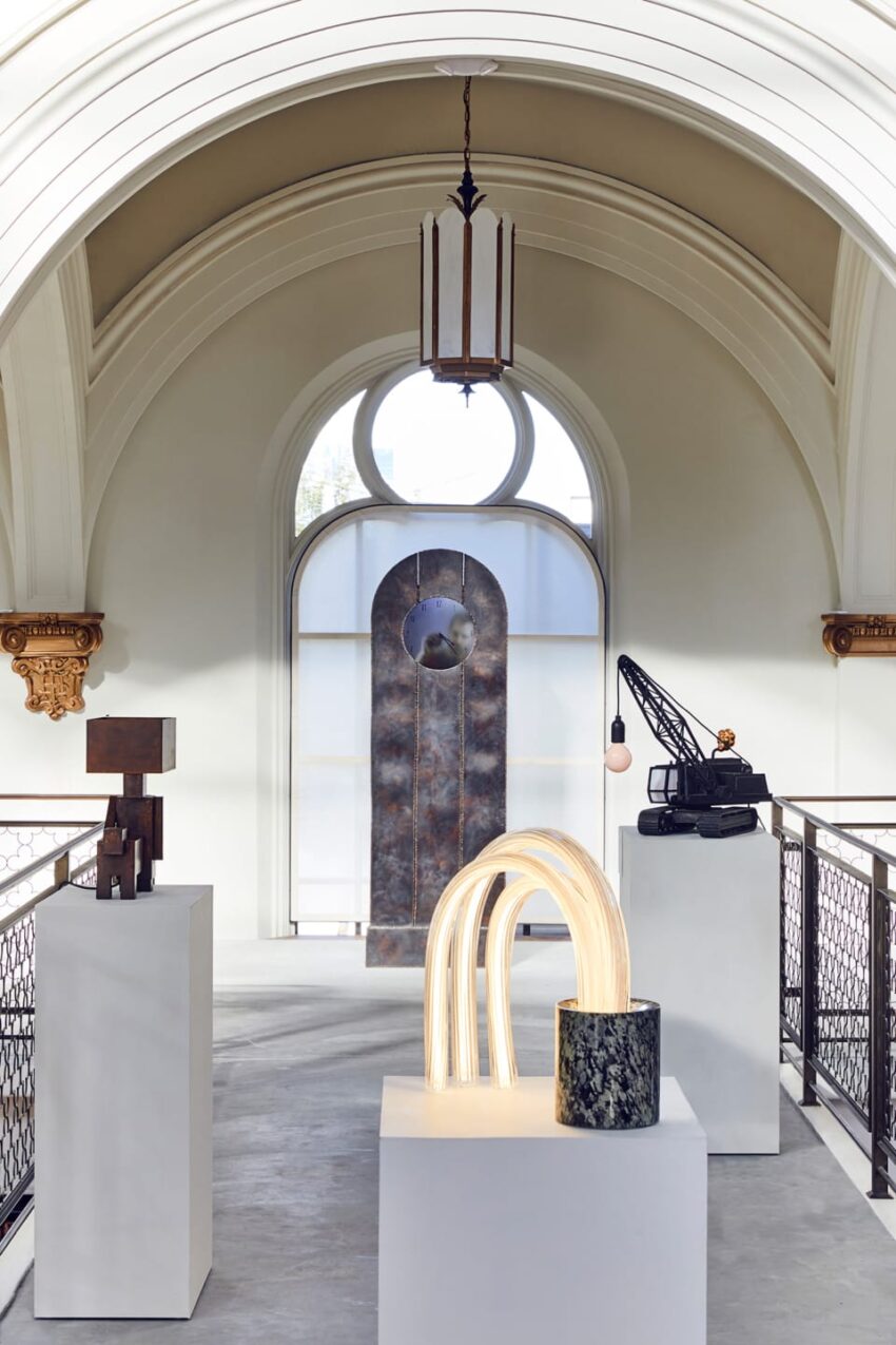 Art sculptures displayed in a bright room with arched ceiling and large round window.
