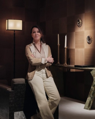Person posing confidently in a stylish, dimly lit room with a modern lamp, candles, and decorative wall pieces.