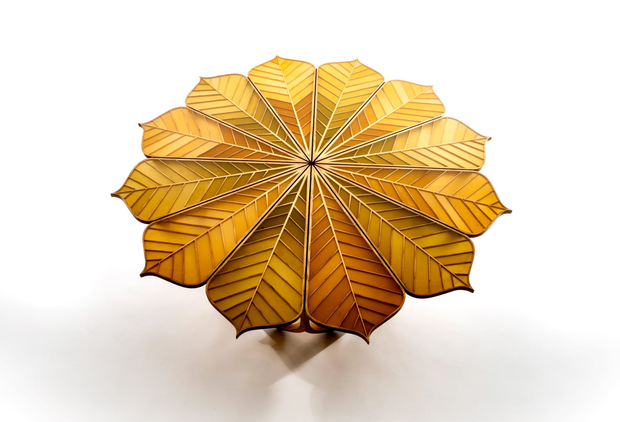 Round wooden table with leaf-shaped segments arranged in a symmetrical pattern, showcasing a natural and artistic design.
