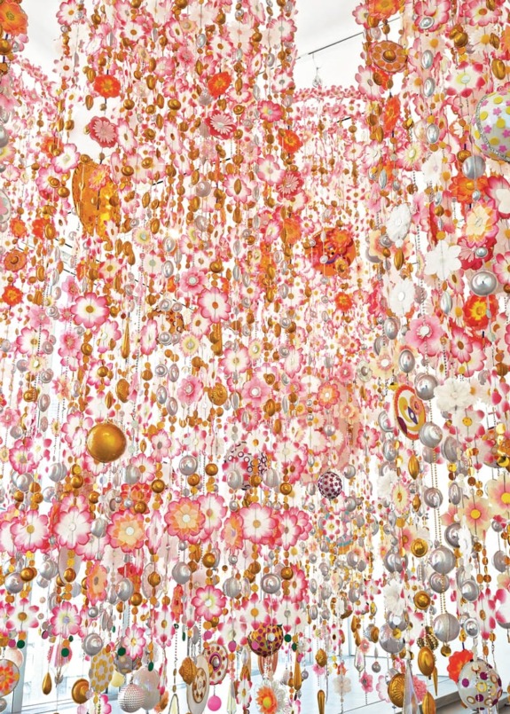 Colorful hanging floral decorations with pink, orange, and gold elements creating a vibrant and whimsical art installation.