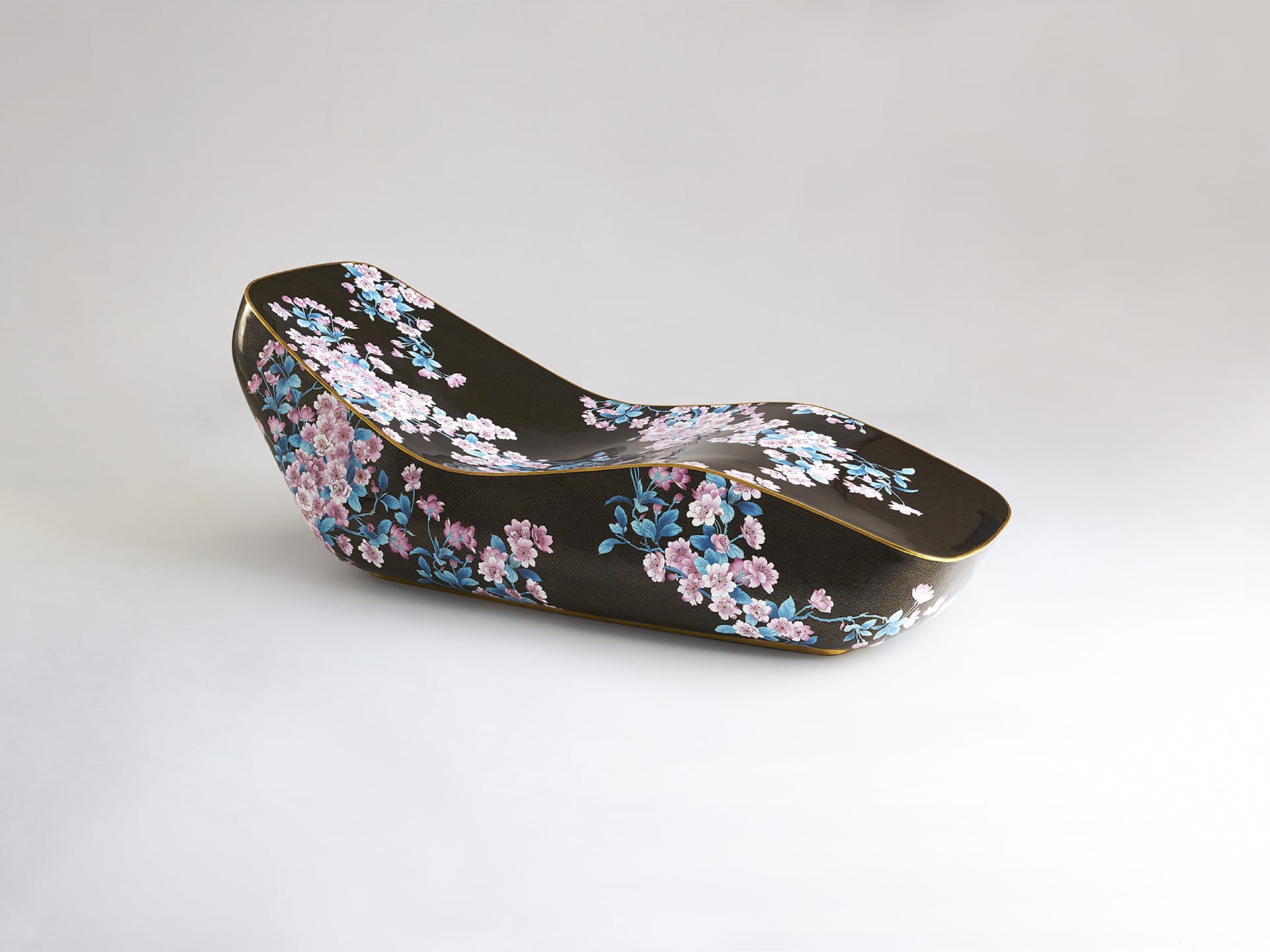 Black chaise longue with pink and white floral pattern on a plain background