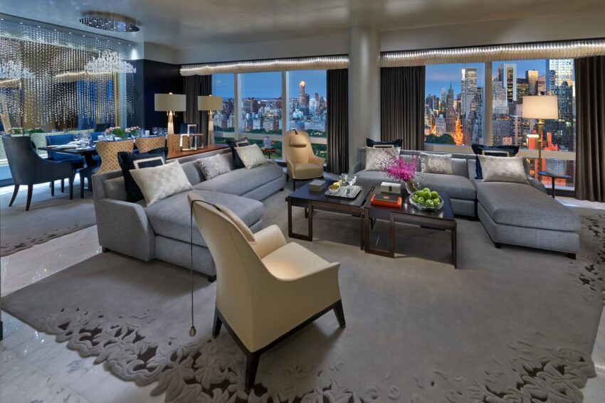 Luxurious living room with modern furniture, large windows, and a cityscape view at night.