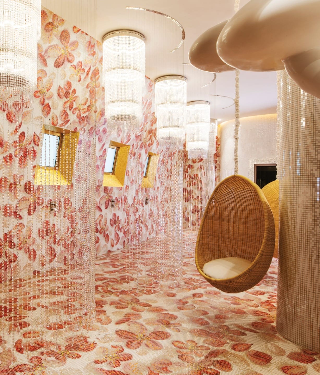 Colorful room with hanging wicker chairs, floral wall and floor patterns, and large ceiling lights in a modern design.