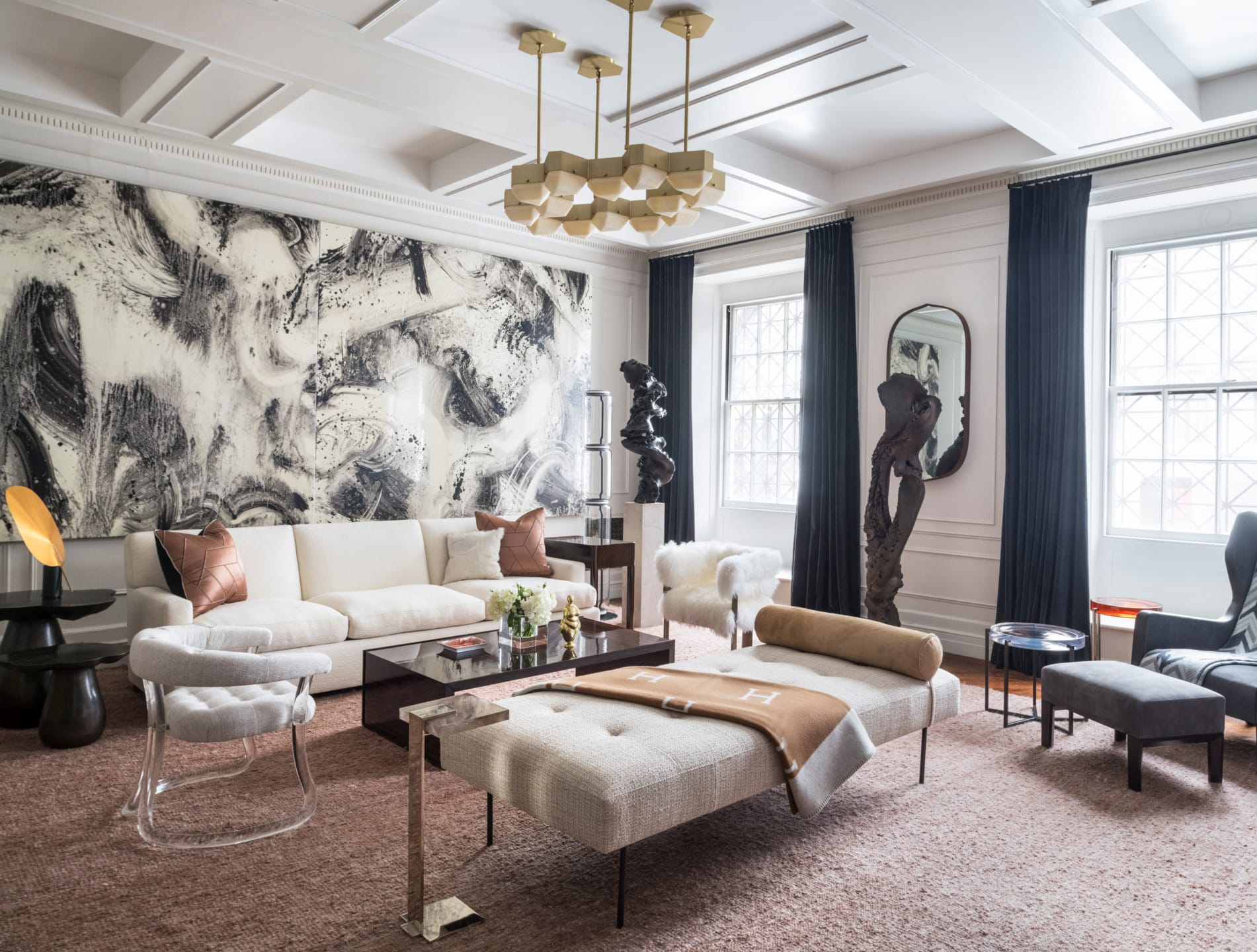 Modern living room with abstract art, plush seating, glass coffee tables, and elegant lighting under a coffered ceiling.