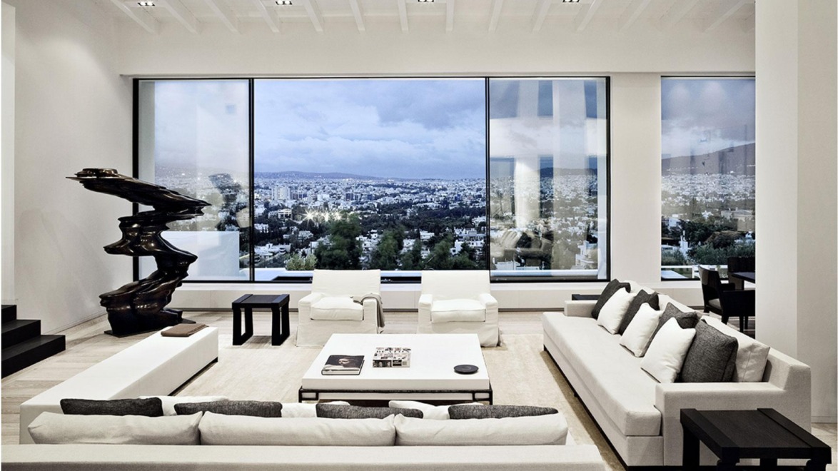 Modern living room with large windows, minimalist decor, white sofas, and a view of the cityscape.