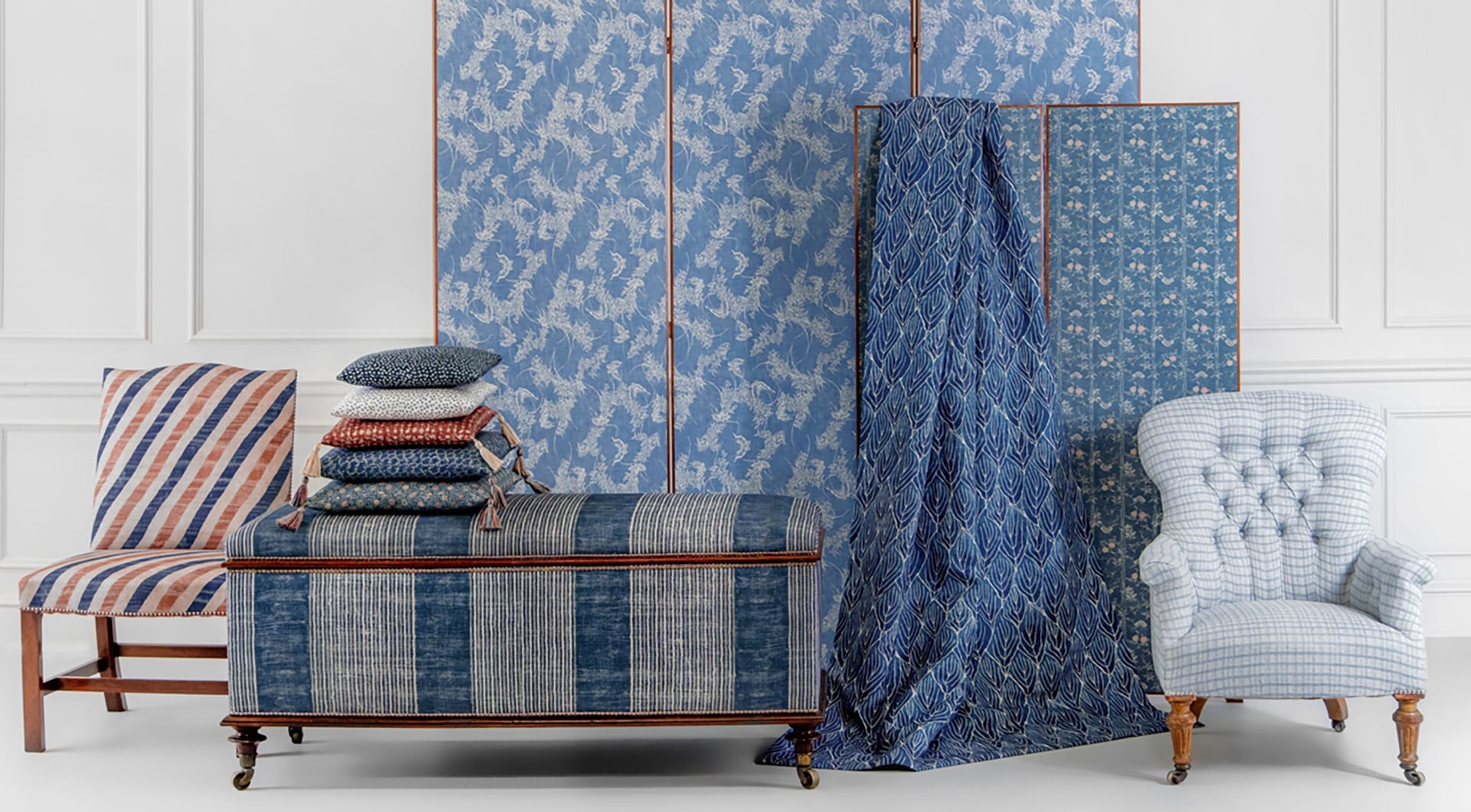 Furniture with blue and striped upholstery, including an armchair, bench with cushions, and decorative screens.