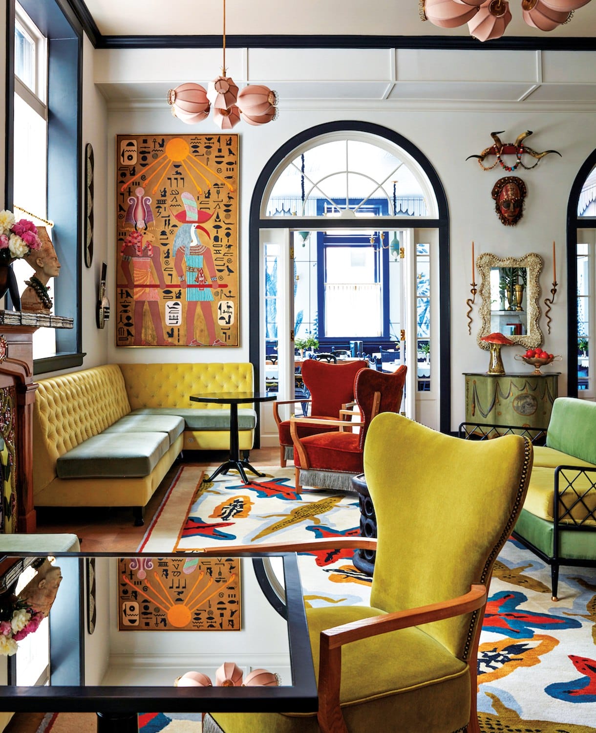 Eclectic living room with colorful furniture, large artwork, and arched windows, creating a vibrant and artistic atmosphere.