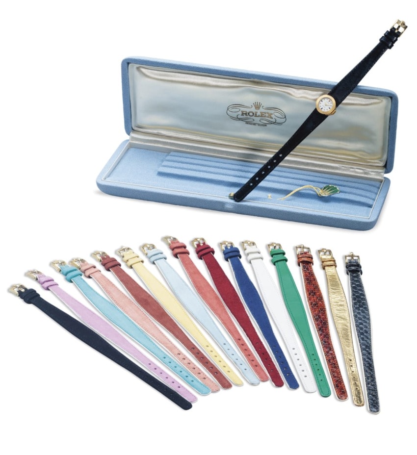 Various colorful watch straps displayed with a Rolex watch in a box.