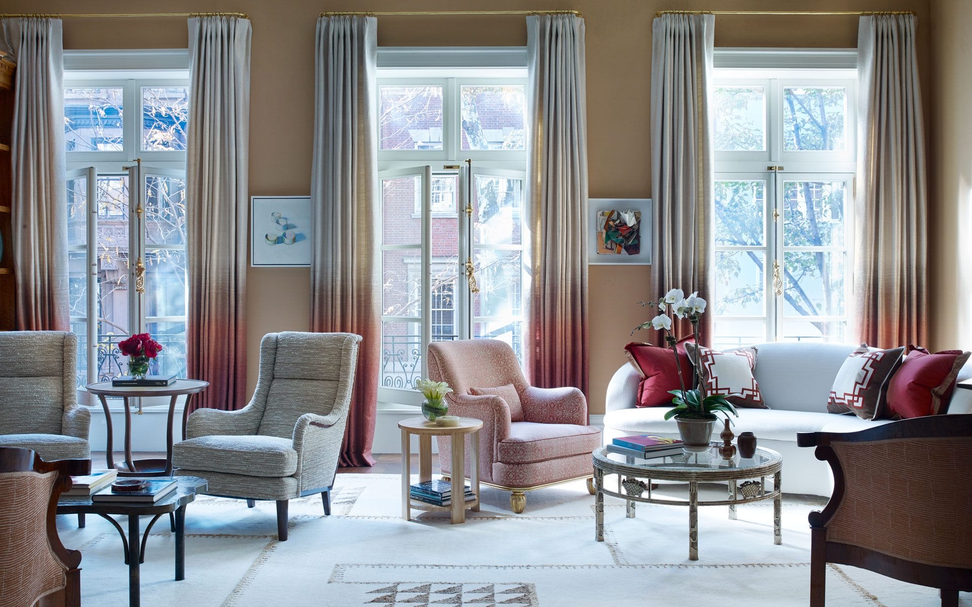 Elegant living room with large windows, stylish armchairs, and a sofa. Soft natural light illuminates the cozy interior space.