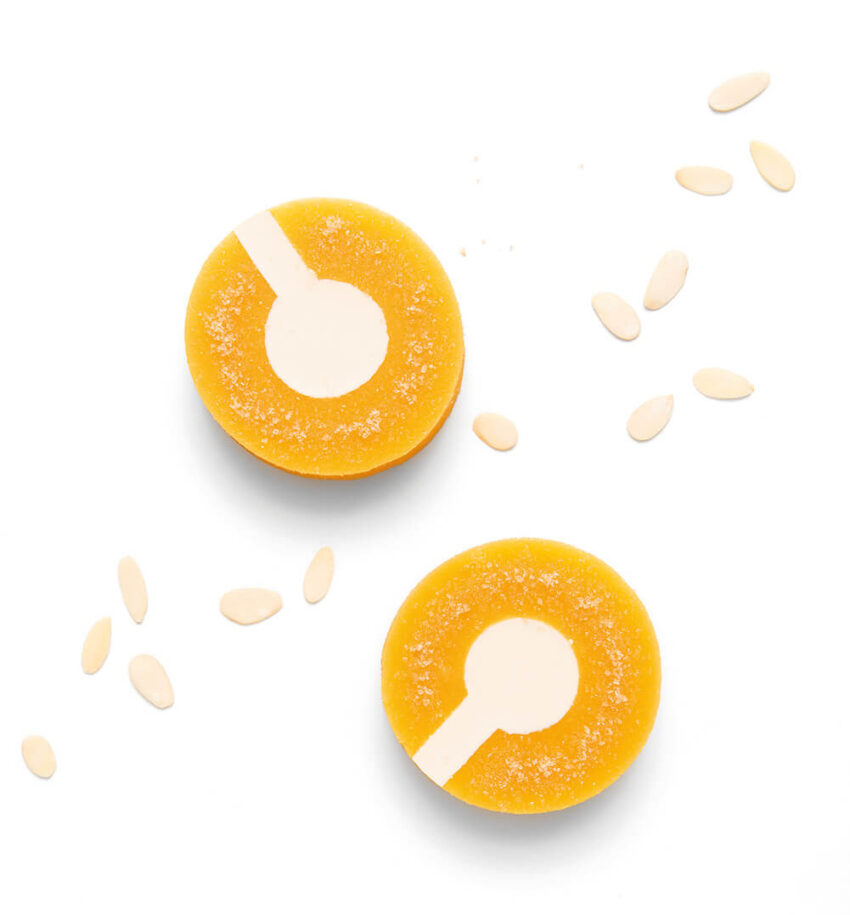 Orange and white circular desserts with almond slices on a white background.