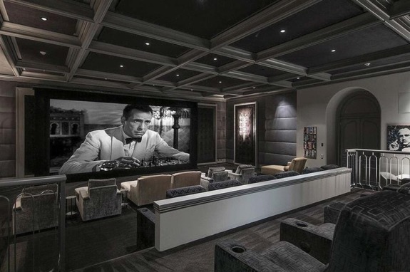 Home theater with plush seating, large screen showing a classic black-and-white film, and elegant ceiling design.