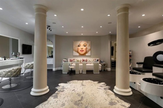 Luxurious, modern beauty salon with manicure stations, salon chairs, and a large portrait on the wall.