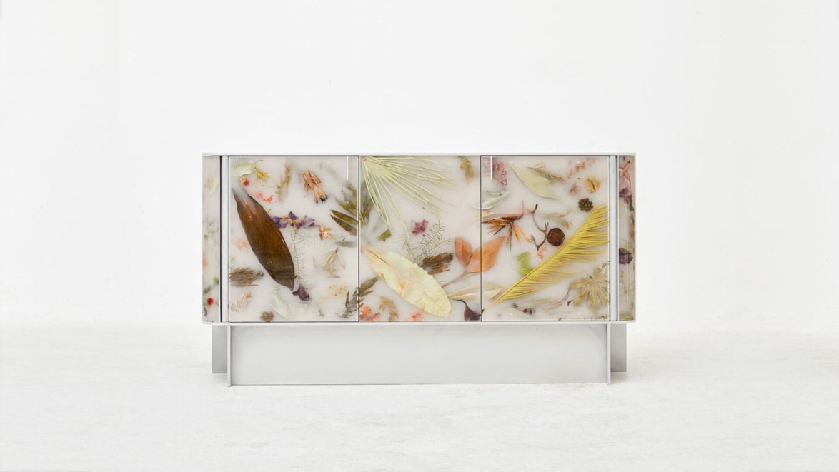 Colorful sideboard with embedded leaves, feathers, and natural elements on a white background.