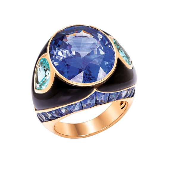 Gold ring with large blue gemstone, surrounded by teardrop aquamarine stones and black enamel accents.