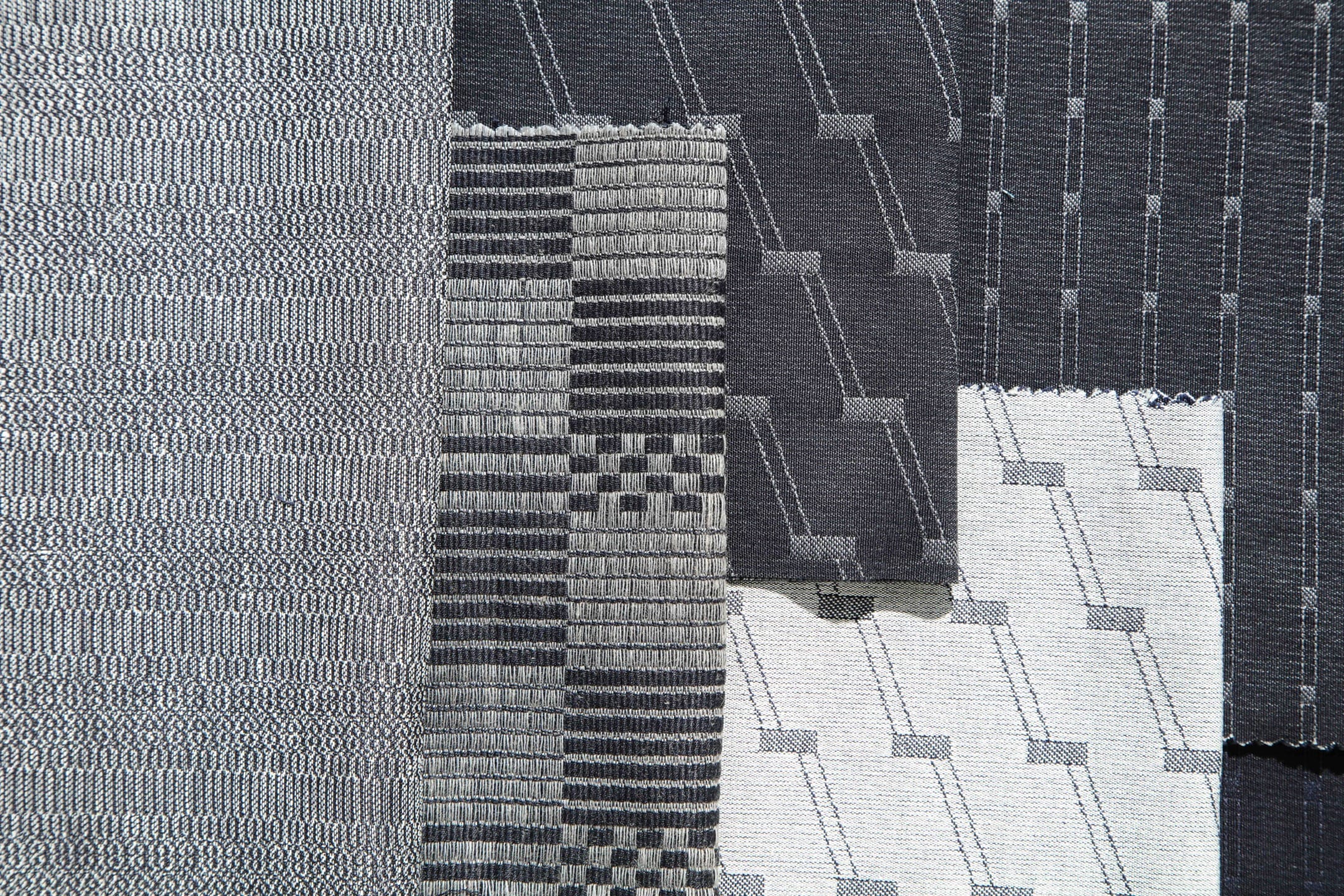 Black and white geometric patterned fabric swatches arranged side by side on a flat surface.