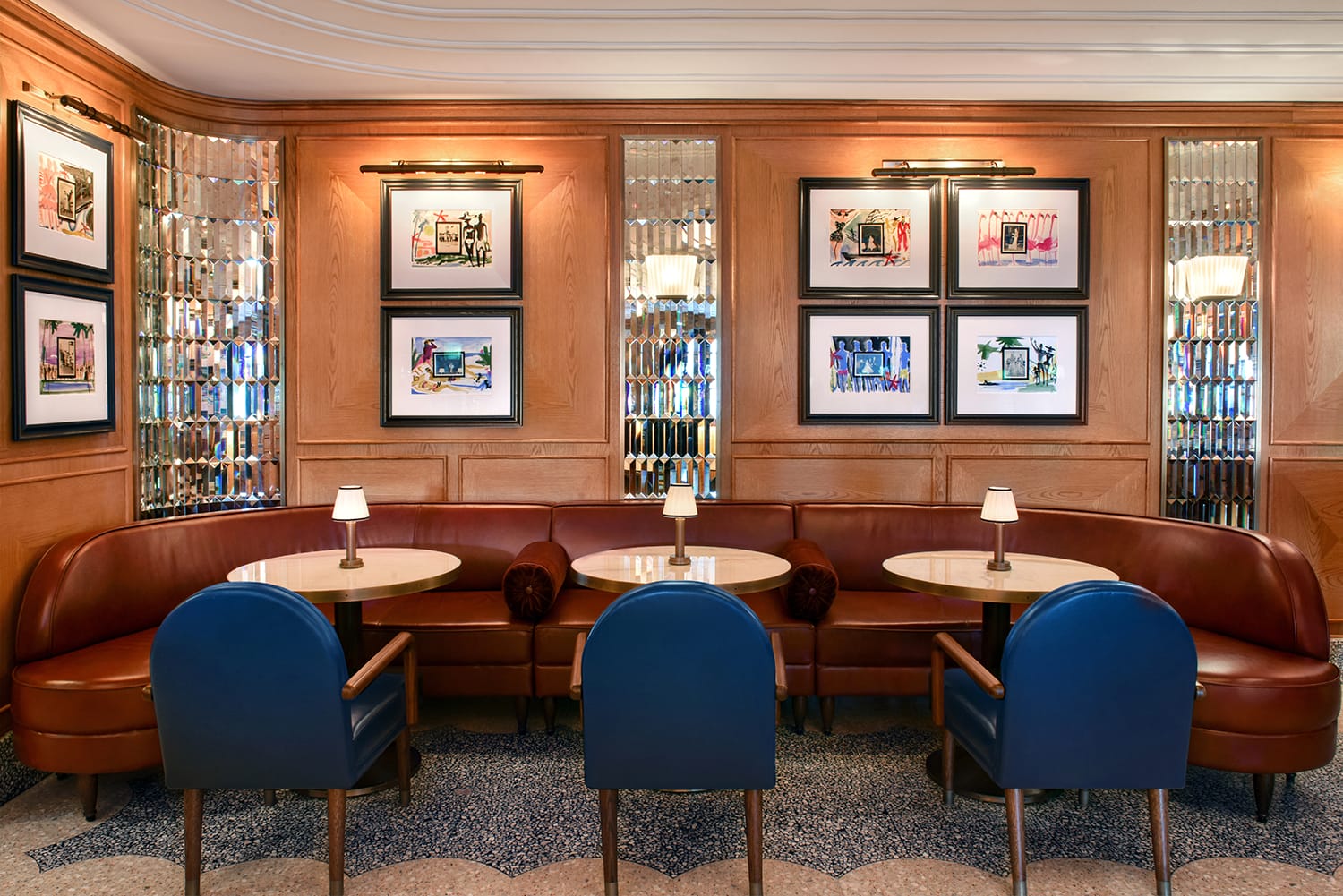 Elegant restaurant seating area with round tables, blue chairs, red booths, and framed art on wood-paneled walls.