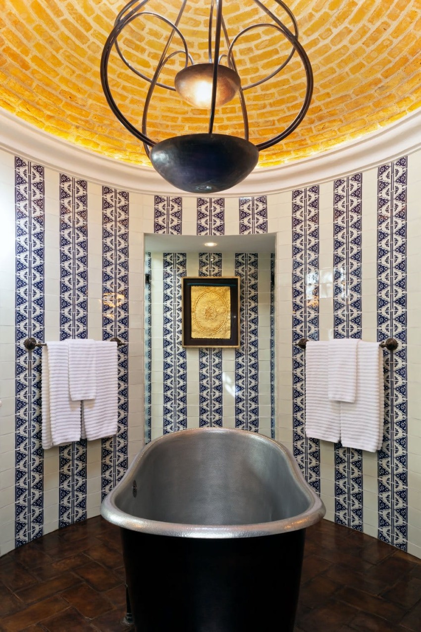 Elegant bathroom with freestanding tub, tiled walls with geometric patterns, and a domed ceiling with warm lighting.