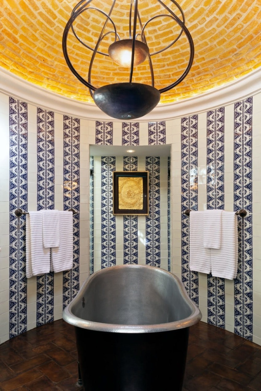 Elegant bathroom with freestanding tub, tiled walls with geometric patterns, and a domed ceiling with warm lighting.
