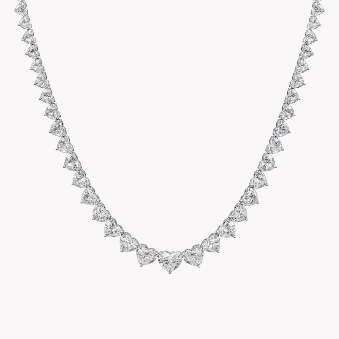 Elegant diamond necklace with heart-shaped stones arranged symmetrically on a thin chain against a neutral background.