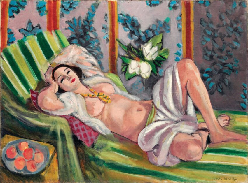 Woman reclining on a green and white striped couch with a floral background, featuring a bowl of fruit on the side table.