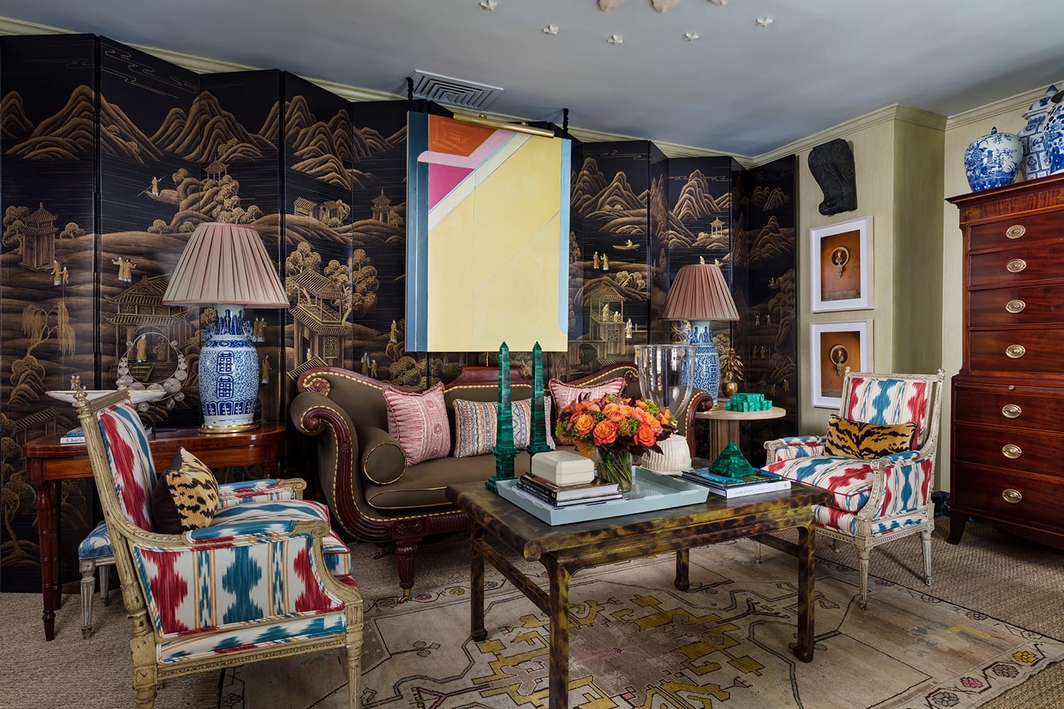 Elegant living room with patterned chairs, floral centerpiece on coffee table, and decorative Asian-style room divider.