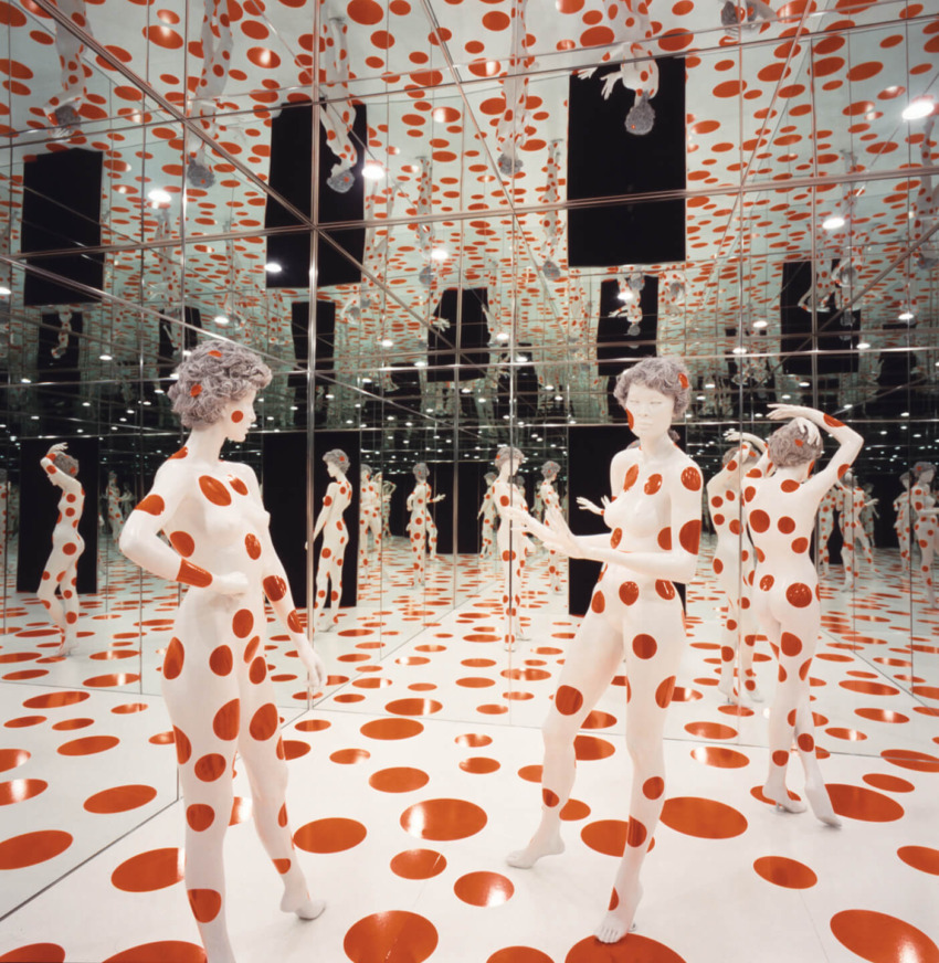 Art installation with mannequins covered in red polka dots in a mirrored room.