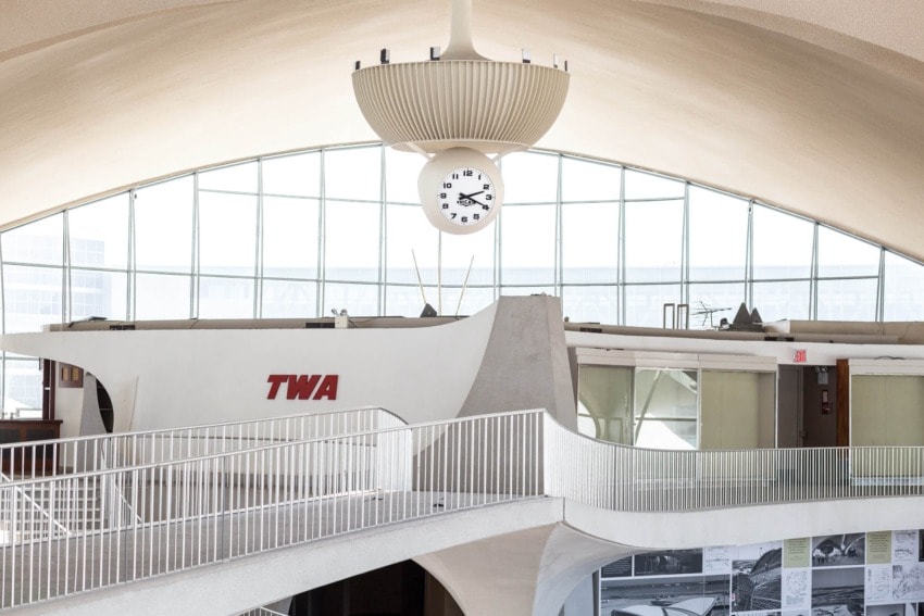 Interior of TWA terminal with mid-century modern clock, large windows, and observation deck at JFK Airport.