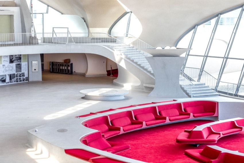 Futuristic interior with curved architecture, red seating, and large windows creating an open and airy atmosphere.