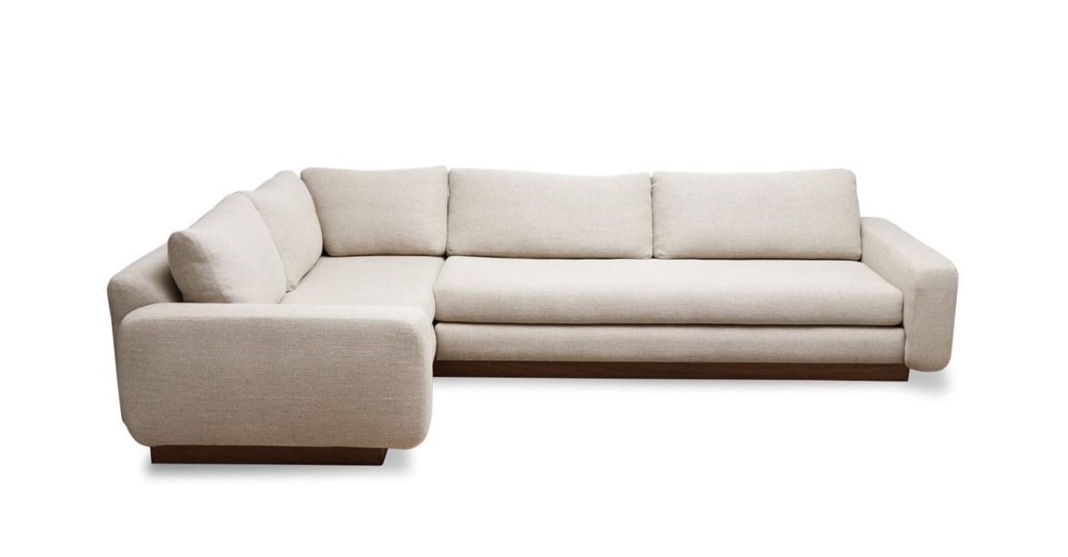 Beige sectional sofa with thick cushions, wooden base, and modern design against a white background.