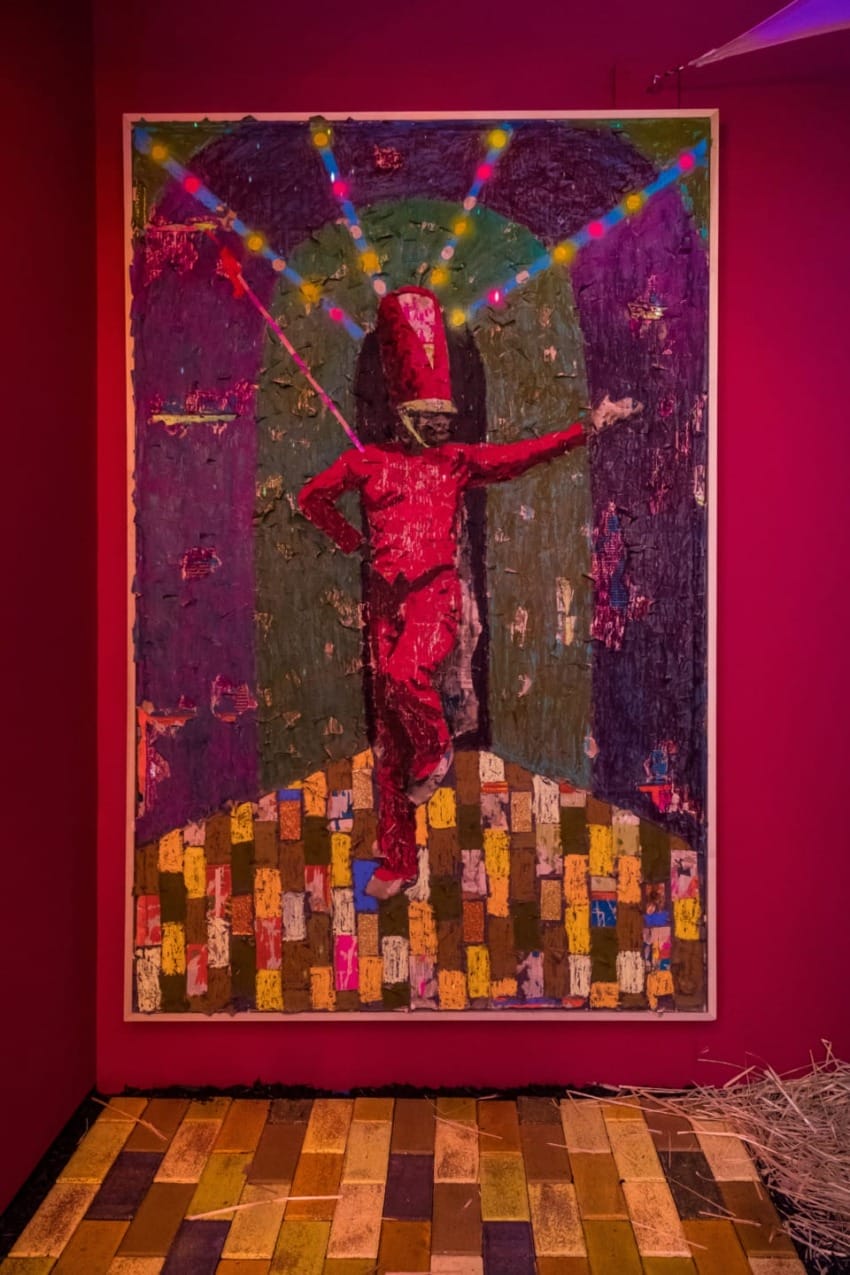 Painting of a figure in a red outfit dancing under colorful lights on a mosaic-style floor, framed by a vibrant setting.