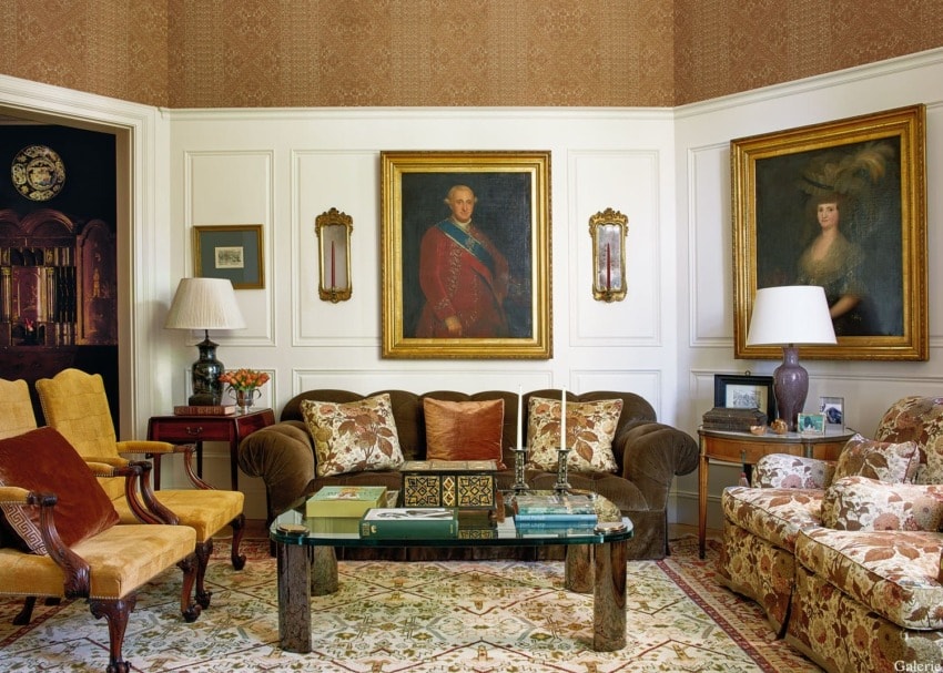 Elegant traditional living room with vintage furniture, ornate paintings, glass coffee table, patterned chairs, and classic decor.