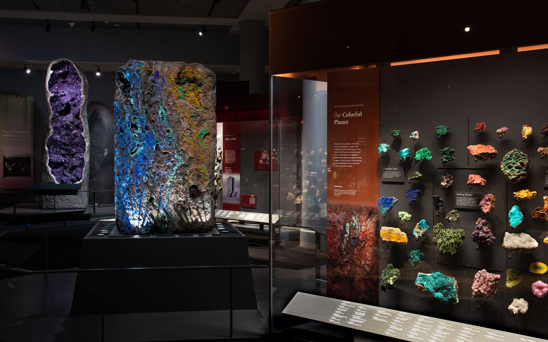 Geology exhibit displaying large mineral formations and colorful rock specimens in a museum setting.