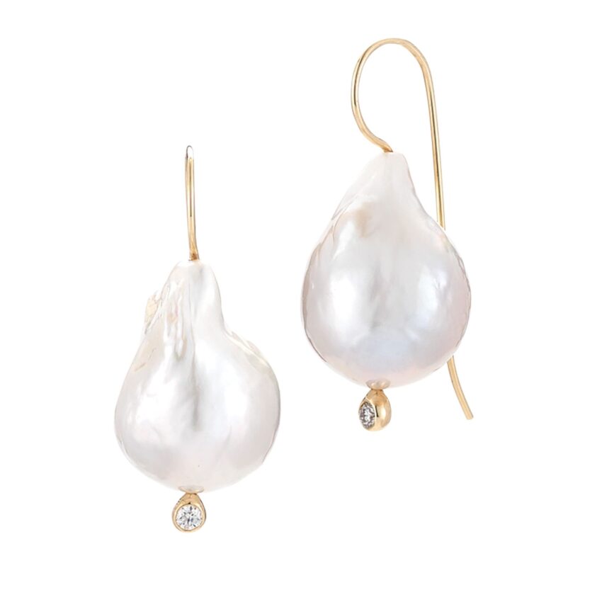 Gold hook earrings with large white baroque pearls and small round diamonds hanging at the bottom.