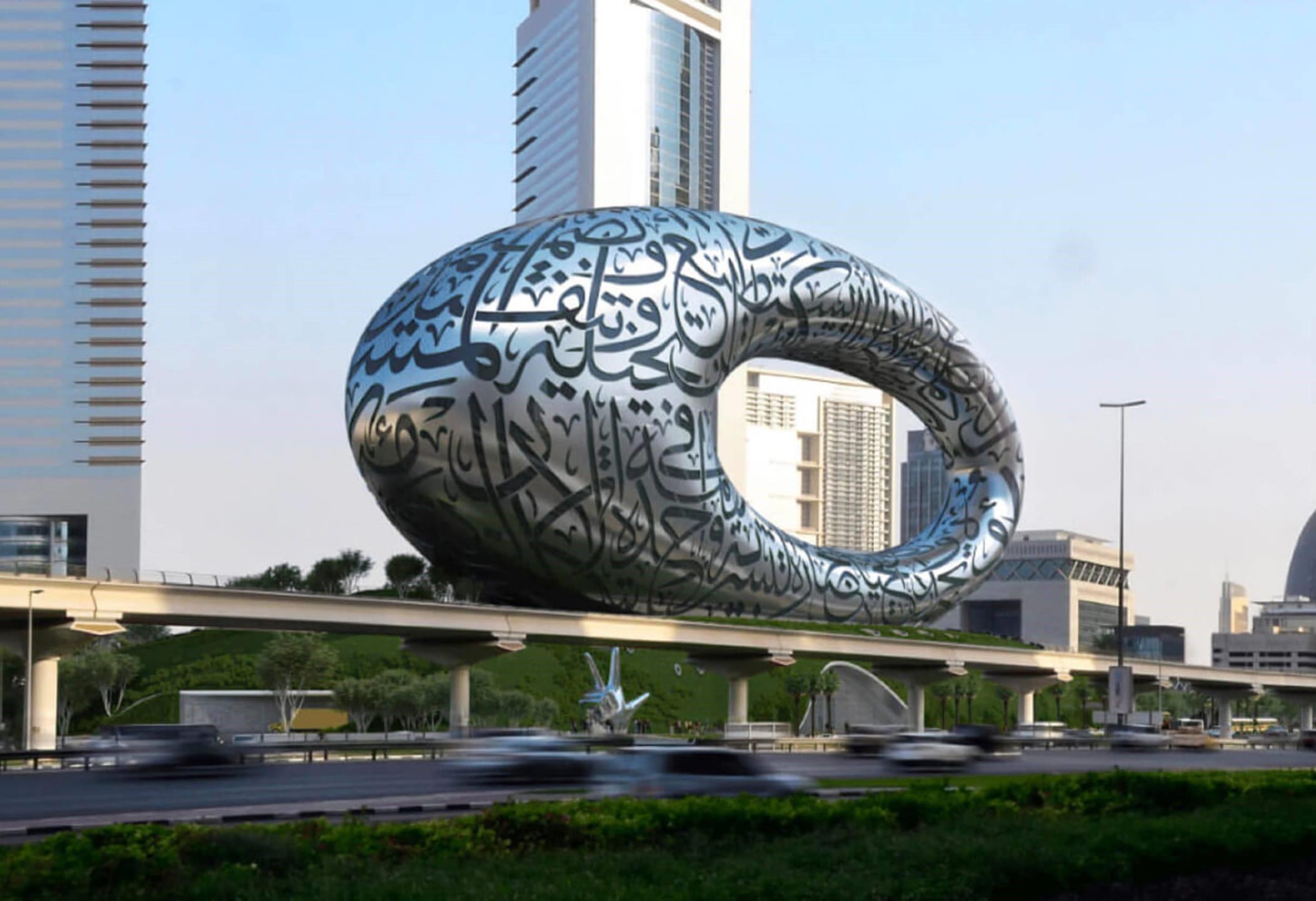 Futuristic building with Arabic calligraphy, known as Museum of the Future, on a busy road with skyscrapers in the background