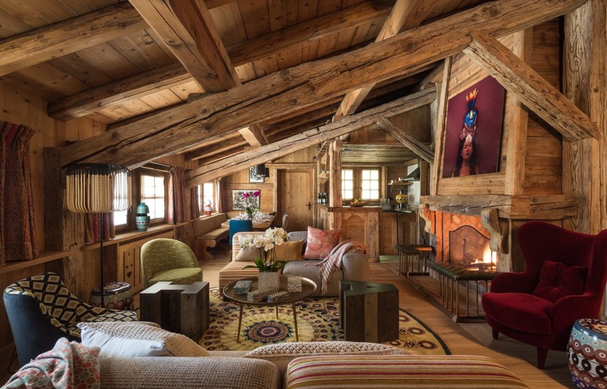 Cozy rustic living room with wooden beams, colorful furniture, and a fireplace, creating a warm, inviting atmosphere.