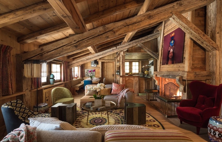 Cozy rustic living room with wooden beams, colorful furniture, and a fireplace, creating a warm, inviting atmosphere.