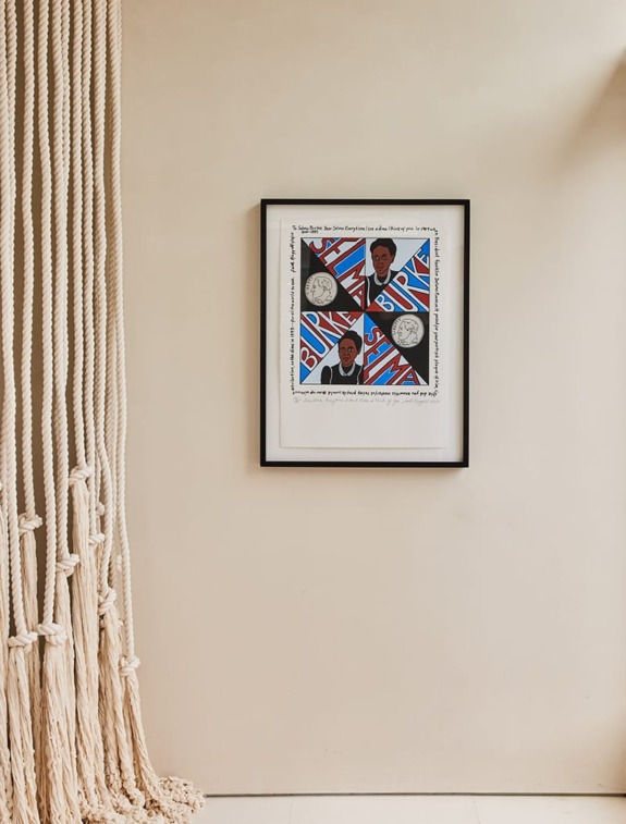 Framed artwork on a beige wall next to a hanging rope decoration.