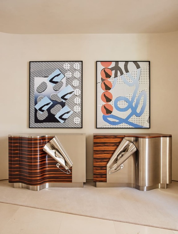 Contemporary art on wall above two modern wood and metal cabinets in a minimalist room.