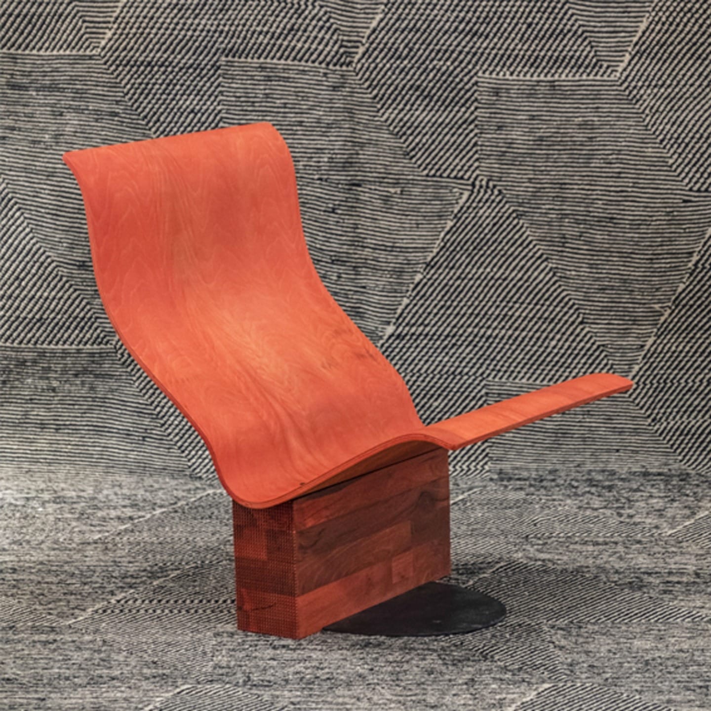 Modern red curved chair on geometric patterned background