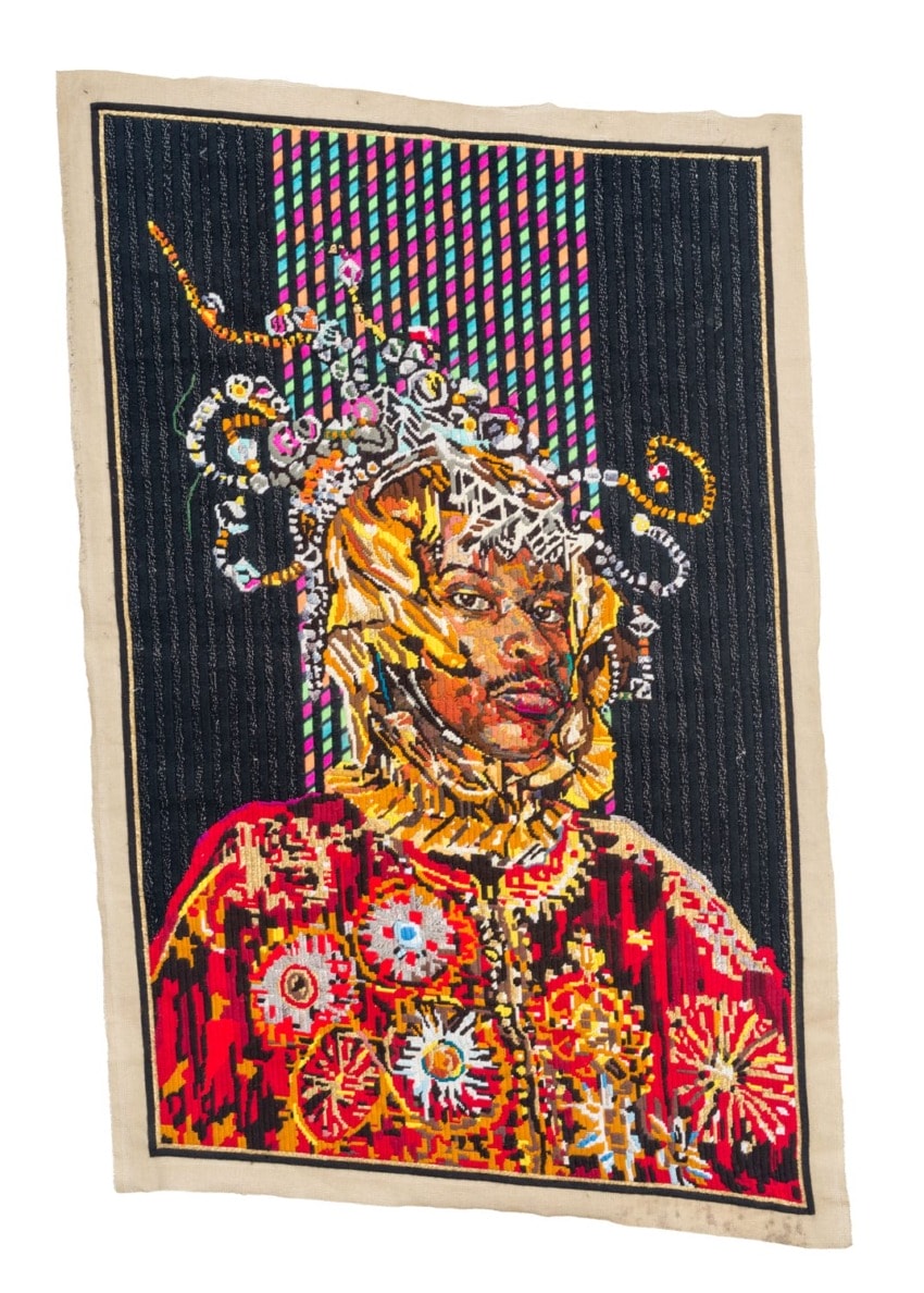 Colorful textile art featuring an intricately detailed portrait with vibrant geometric patterns and embellishments