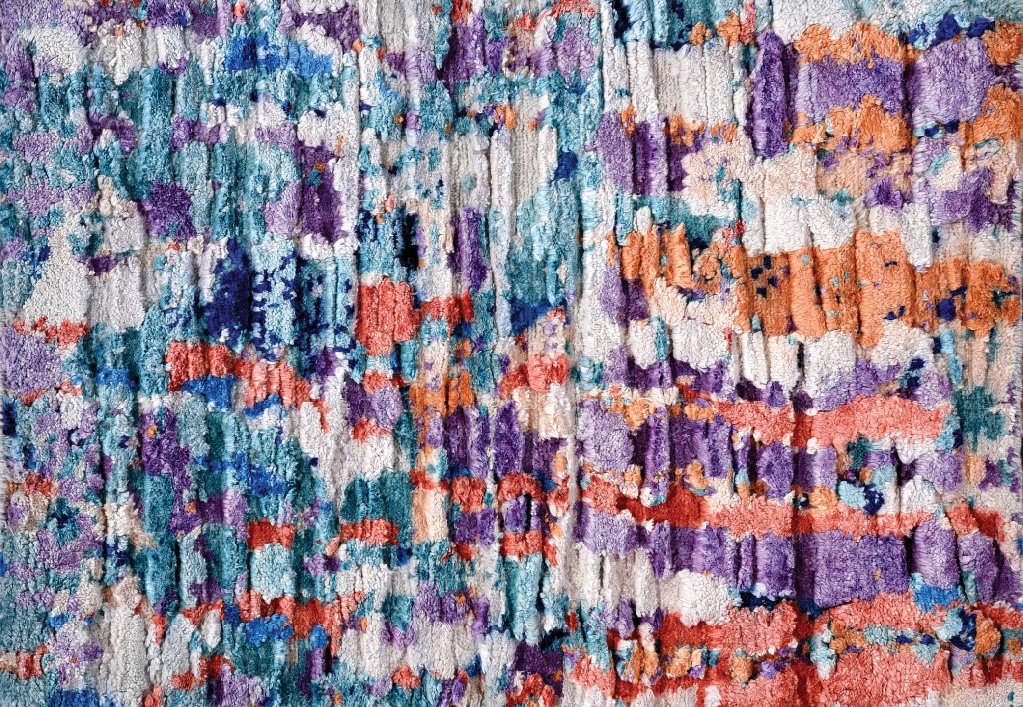 Abstract colorful textile texture with a mix of blue, purple, orange, and white shades creating a vivid, artistic pattern.