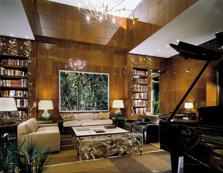 Luxurious modern living room with leather chairs, a grand piano, bookshelf, artwork, and elegant decor elements.