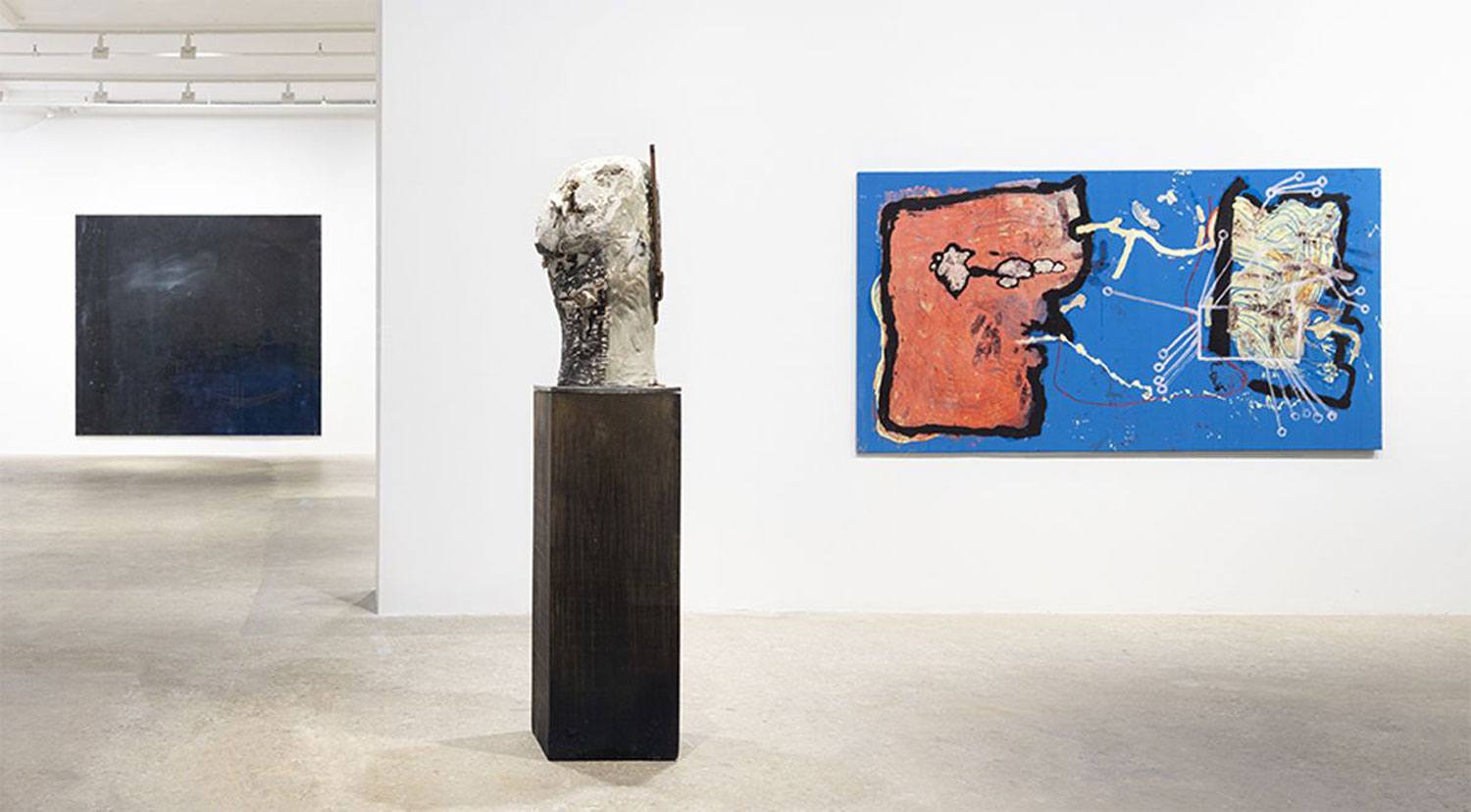 Contemporary art gallery with abstract paintings on walls and a sculpted head on a pedestal in the center.